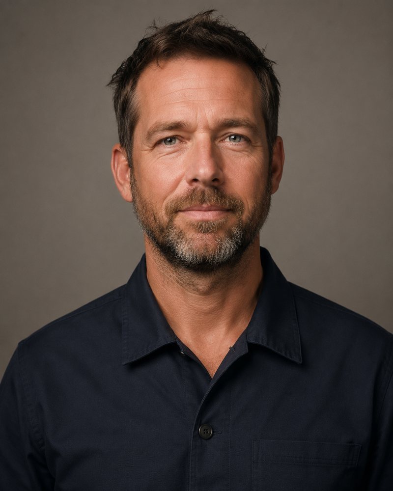 Portret van een man van ongeveer 45 met een korte baard en een effen donker werkhemd